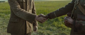 Movie still from “1917” (2019), directed by Sam Mendes – Two men shaking hands in a grassy field; Close Up shot, High angle