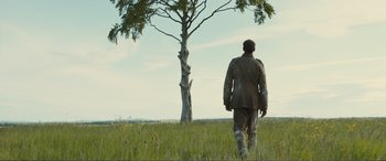 Movie still from “1917” (2019), directed by Sam Mendes – A man walking in a field near a tree; Wide shot, Low angle