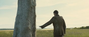 Movie still from “1917” (2019), directed by Sam Mendes – A man standing next to a tree pointing to the sky; Wide shot, Low angle