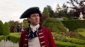Movie still from “Outlander” (2014), created by Ronald D. Moore – A man in a red jacket and a black hat; Medium shot, Low angle
