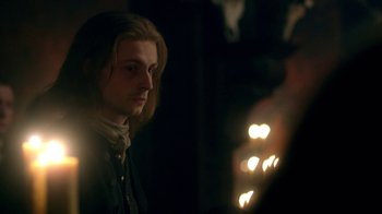 Movie still from “Outlander” (2014), created by Ronald D. Moore – A man with long blonde hair standing in a dark room; Close Up shot, Over the shoulder angle