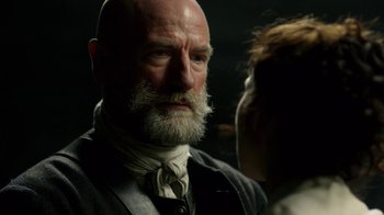 Movie still from “Outlander” (2014), created by Ronald D. Moore – An old man with a beard and a white mustache; Close Up shot, Over the shoulder angle