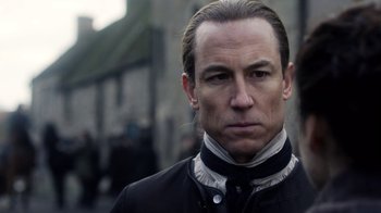 Movie still from “Outlander” (2014), created by Ronald D. Moore – A person wearing a suit and tie; Close Up shot, Over the shoulder angle