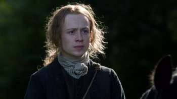 Movie still from “Outlander” (2014), created by Ronald D. Moore – A man with long blonde hair wearing a neck scarf; Close Up shot, Low angle