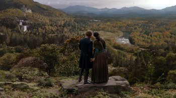 Movie still from “Outlander” (2014), created by Ronald D. Moore – A man and a woman standing on top of a mountain; Extreme Wide shot, High angle