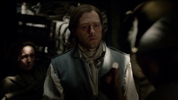 Movie still from “Outlander” (2014), created by Ronald D. Moore – A man in a vest holding something in his hand; Close Up shot, Over the shoulder angle