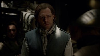 Movie still from “Outlander” (2014), created by Ronald D. Moore – A man with long brown hair wearing a vest; Close Up shot, Over the shoulder angle