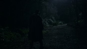 Movie still from “Outlander” (2014), created by Ronald D. Moore – A man standing in the dark on a path; Extreme Wide shot, Over the shoulder angle