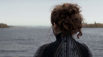 Movie still from “Outlander” (2014), created by Ronald D. Moore – A woman standing in front of a body of water; Close Up shot, Over the shoulder angle
