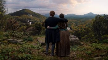 Movie still from “Outlander” (2014), created by Ronald D. Moore – A man and a woman standing on top of a hill; Extreme Wide shot, High angle