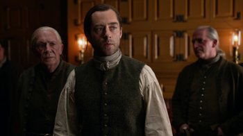 Movie still from “Outlander” (2014), created by Ronald D. Moore – A man wearing a vest and a white shirt standing next to another man wearing a vest; Medium shot, Over the shoulder angle