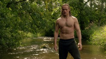 Movie still from “Outlander” (2014), created by Ronald D. Moore – A man standing in the water near a body of water; Medium shot, Over the shoulder angle
