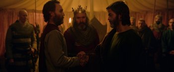 Movie still from “Outlaw King” (2018), directed by David Mackenzie – A couple of men standing next to each other holding hands; Medium shot, Over the shoulder angle