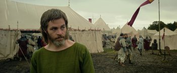 Movie still from “Outlaw King” (2018), directed by David Mackenzie – A man with a beard standing in front of tents; Close Up shot, Over the shoulder angle