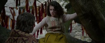 Movie still from “Outlaw King” (2018), directed by David Mackenzie – A young girl is sitting on a tree branch; Medium shot, Over the shoulder angle
