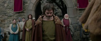 Movie still from “Outlaw King” (2018), directed by David Mackenzie – A group of men standing around a stone wall; Medium shot, Low angle