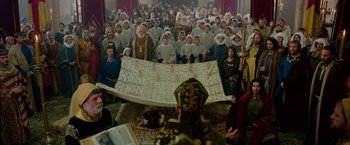 Movie still from “Outlaw King” (2018), directed by David Mackenzie – A group of people dressed in white sitting in front of a large sheet of paper; Wide shot, High angle