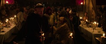 Movie still from “Outlaw King” (2018), directed by David Mackenzie – A man standing in front of a group of people holding lit candles; Medium shot, Over the shoulder angle