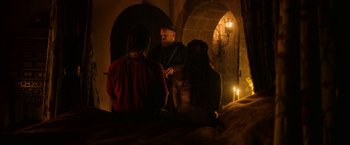 Movie still from “Outlaw King” (2018), directed by David Mackenzie – A group of people standing around in a dark room; Medium shot, Over the shoulder angle