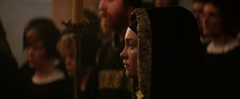 Movie still from “Outlaw King” (2018), directed by David Mackenzie – A woman with a head covering looking to her left; Close Up shot, Over the shoulder angle