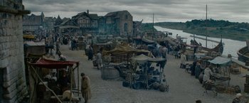 Movie still from “Outlaw King” (2018), directed by David Mackenzie – A group of people standing around a market area; Extreme Wide shot, High angle