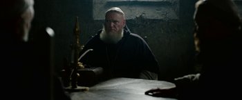 Movie still from “Outlaw King” (2018), directed by David Mackenzie – A man with a long beard sitting at a table; Medium shot, Over the shoulder angle