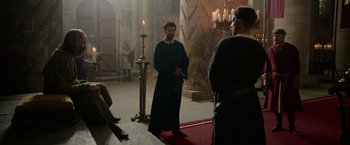 Movie still from “Outlaw King” (2018), directed by David Mackenzie – A man standing in front of a pillar in a room; Wide shot, Over the shoulder angle