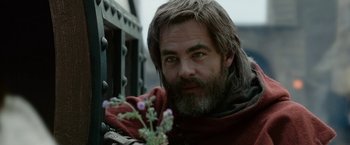Movie still from “Outlaw King” (2018), directed by David Mackenzie – A man with long hair and a beard holding a flower; Close Up shot, Over the shoulder angle