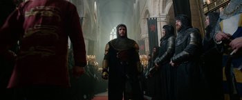 Movie still from “Outlaw King” (2018), directed by David Mackenzie – A man dressed as a medieval knight in front of a group of people; Wide shot, Low angle