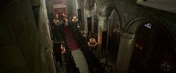 Movie still from “Outlaw King” (2018), directed by David Mackenzie – A large group of people sitting in front of candles in a church; Extreme Wide shot, High angle