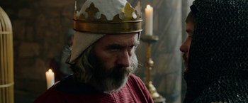 Movie still from “Outlaw King” (2018), directed by David Mackenzie – A man with a beard wearing a gold crown; Close Up shot, Low angle