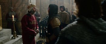 Movie still from “Outlaw King” (2018), directed by David Mackenzie – A group of men standing next to each other in a room; Medium shot, Over the shoulder angle