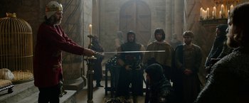 Movie still from “Outlaw King” (2018), directed by David Mackenzie – A group of people standing in a room holding swords; Wide shot, Over the shoulder angle