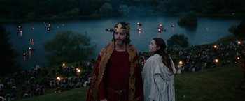 Movie still from “Outlaw King” (2018), directed by David Mackenzie – A man and a woman dressed in medieval garb in front of a body of water; Medium shot, High angle