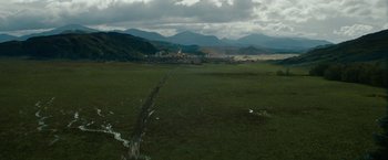 Movie still from “Outlaw King” (2018), directed by David Mackenzie – An aerial view of a green field with mountains in the background; Extreme Wide shot, High angle
