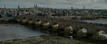 Movie still from “Outlaw King” (2018), directed by David Mackenzie – A view of a city from across a river; Extreme Wide shot, High angle