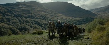 Movie still from “Outlaw King” (2018), directed by David Mackenzie – A group of people standing on top of a grass covered hill; Wide shot, Low angle