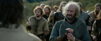 Movie still from “Outlaw King” (2018), directed by David Mackenzie – A group of men in medieval garb are marching in a line; Medium shot, Over the shoulder angle