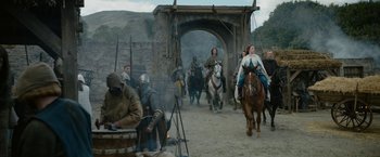 Movie still from “Outlaw King” (2018), directed by David Mackenzie – A group of people riding horses on a dirt road; Wide shot, Low angle