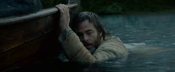 Movie still from “Outlaw King” (2018), directed by David Mackenzie – A man is holding a boat in a body of water; Medium shot, High angle