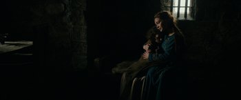 Movie still from “Outlaw King” (2018), directed by David Mackenzie – A woman and a child sitting in a dark room; Medium shot, Low angle
