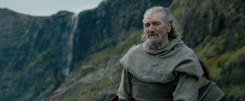 Movie still from “Outlaw King” (2018), directed by David Mackenzie – An older man with a long beard wearing a gray coat; Close Up shot, Low angle
