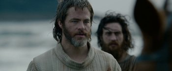 Movie still from “Outlaw King” (2018), directed by David Mackenzie – A man with long hair and beard standing next to another man with long hair; Medium shot, Over the shoulder angle