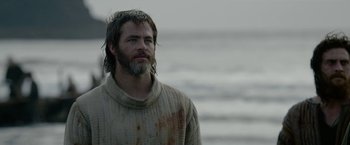 Movie still from “Outlaw King” (2018), directed by David Mackenzie – A man standing on the beach in a sweater; Medium shot, Low angle