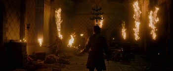 Movie still from “Outlaw King” (2018), directed by David Mackenzie – A man holding a sword in front of a fire pit; Wide shot, High angle