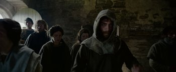 Movie still from “Outlaw King” (2018), directed by David Mackenzie – A group of people walking in a dark room; Medium shot, Low angle