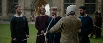 Movie still from “Outlaw King” (2018), directed by David Mackenzie – Two men in medieval garb holding a bow and arrow; Medium shot, Over the shoulder angle