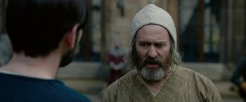 Movie still from “Outlaw King” (2018), directed by David Mackenzie – A man with a beard and a white hat is talking to another man; Close Up shot, Over the shoulder angle