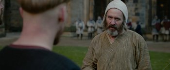 Movie still from “Outlaw King” (2018), directed by David Mackenzie – A man with a beard wearing a white hat; Close Up shot, Over the shoulder angle