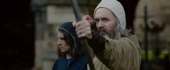Movie still from “Outlaw King” (2018), directed by David Mackenzie – A man with a long beard holding a spear; Close Up shot, Over the shoulder angle
